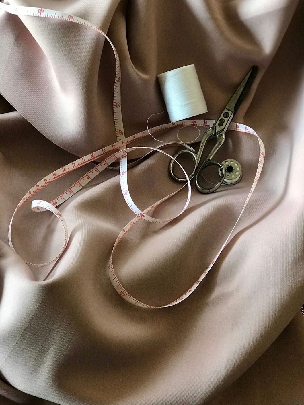 Tape measure, scissors, and thread on fabric