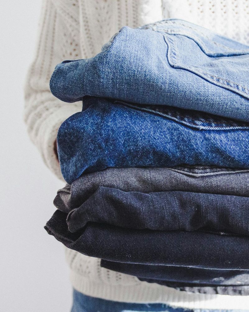 Person holding a neat stack of folded jeans