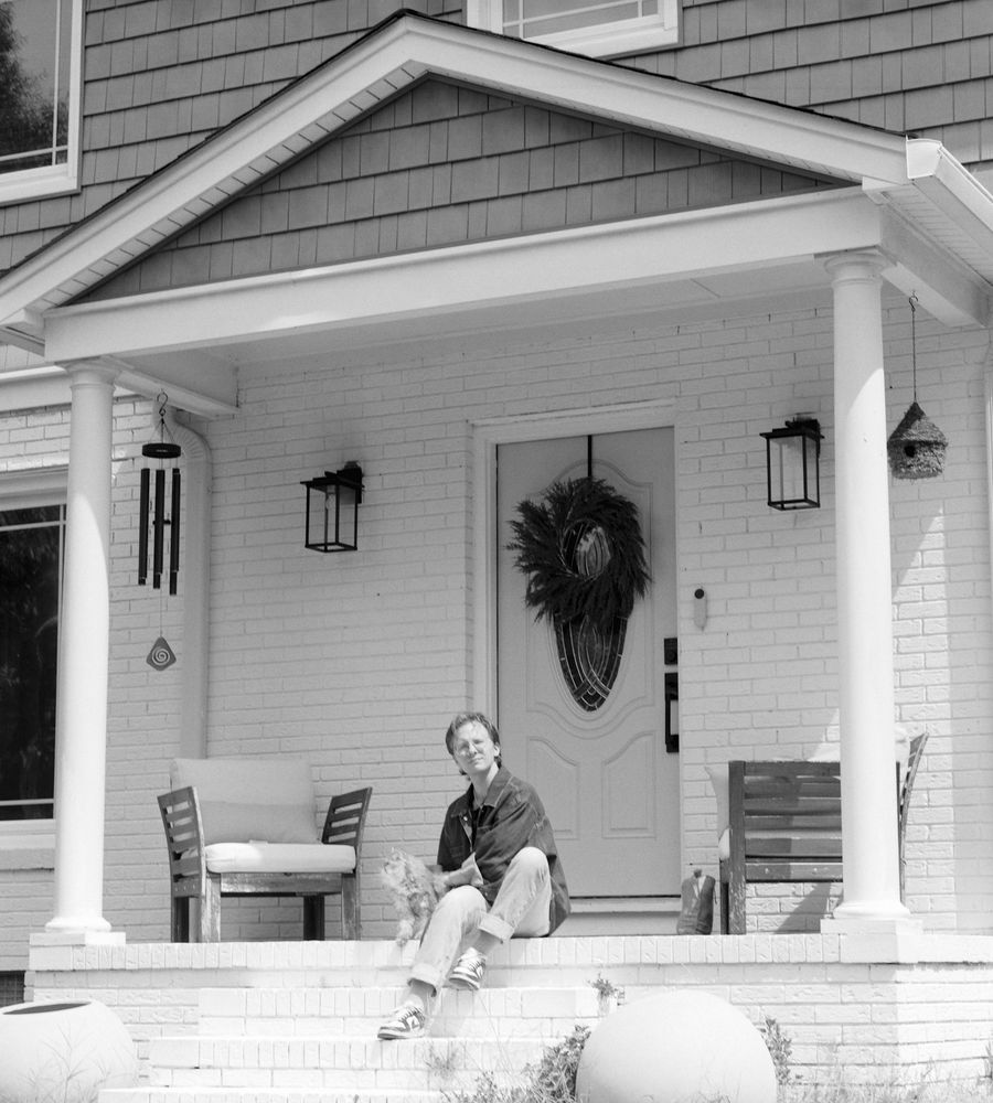 Person relaxing on the front porch steps of a white house