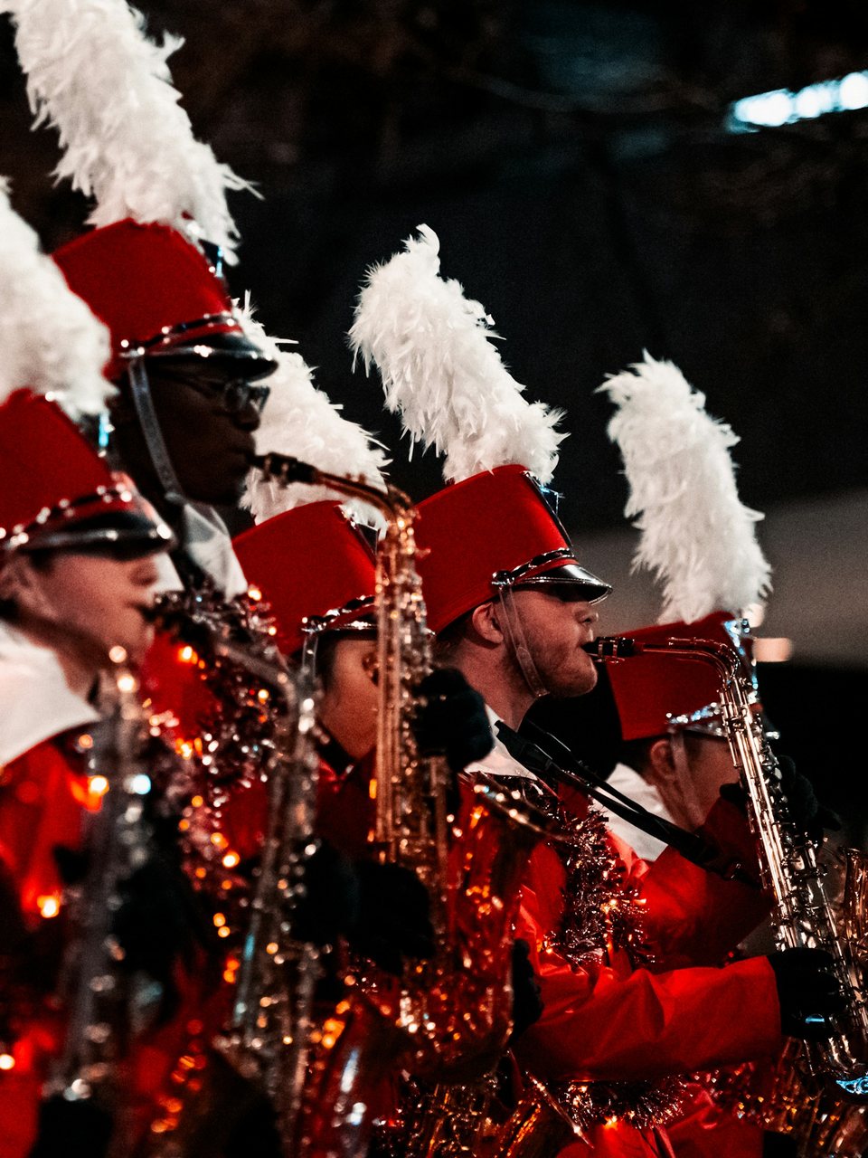 Marching band in red uniforms and white-plumed hats playing saxophones