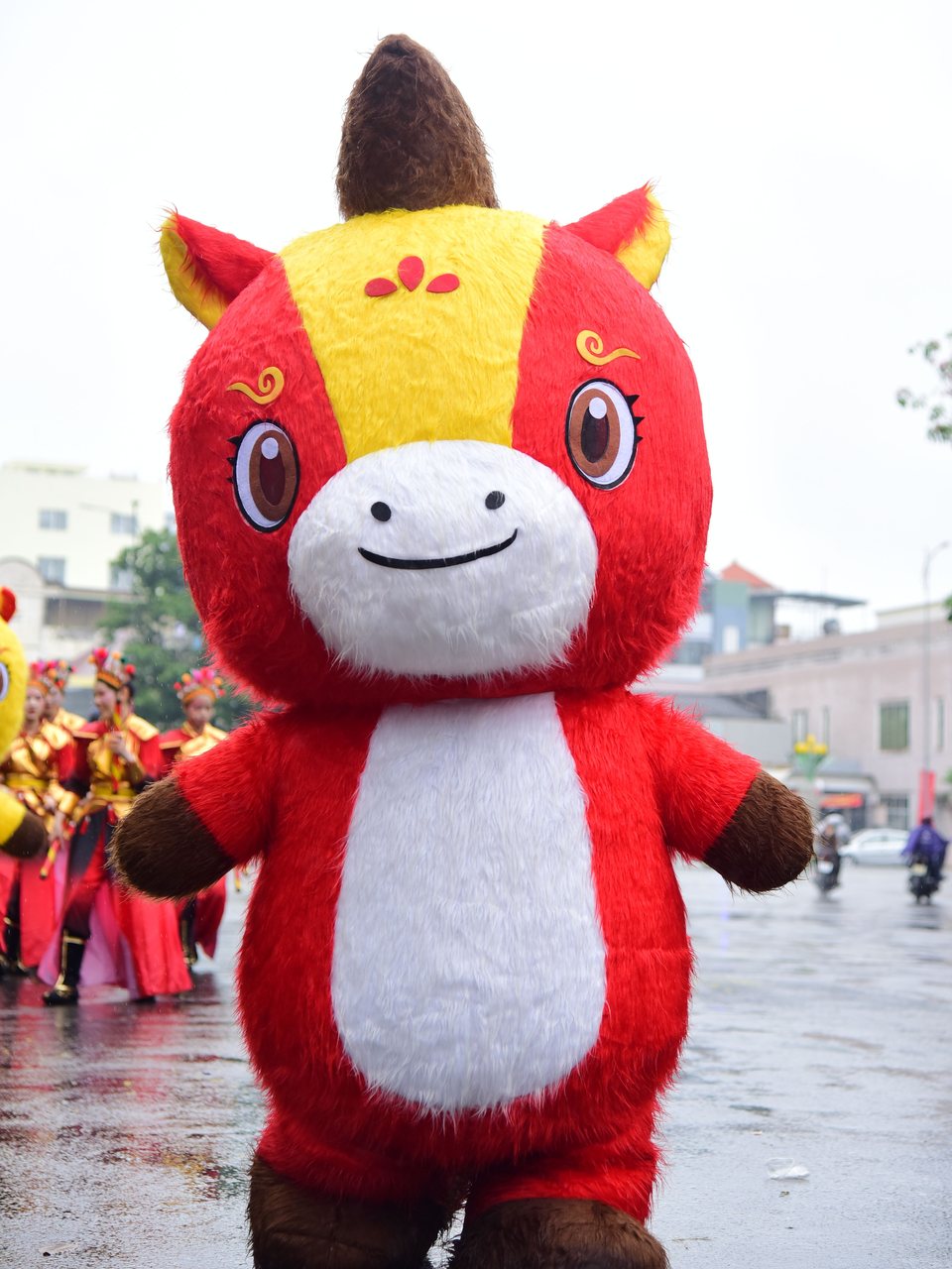 Fuzzy red and yellow mascot costume walking in a parade